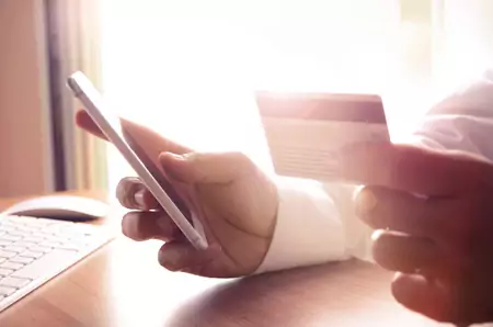 45216284 - closeup of man's hands holding credit cards and using mobile phone. concept for m-commerce, online shopping, m-banking, internet security.