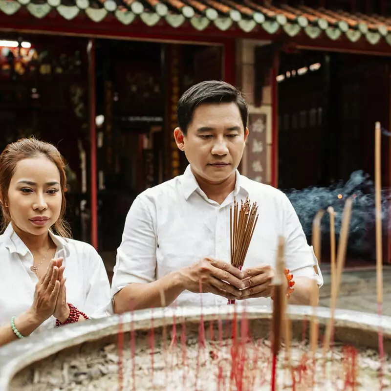 woman man praying temple with burning incense resize